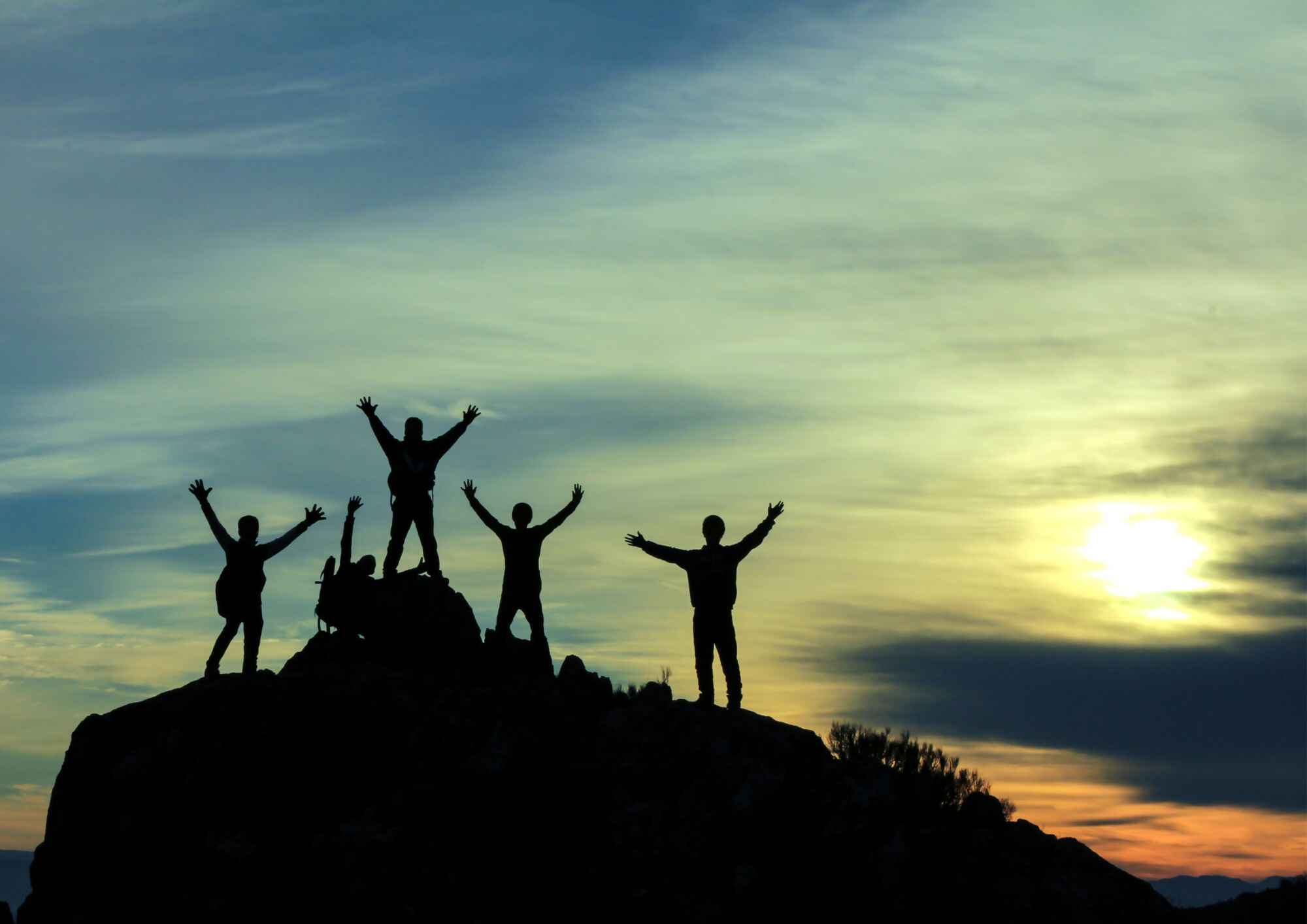Hikers silhouetted on a mountain ridge at sunset